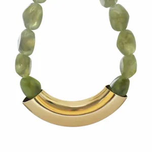 Closeup detail of green resin bead necklace with a statement gold tone curved metal tube.
