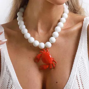 Collana di perle bianche con ciondolo granchio rosso, ideale per le vacanze estive.