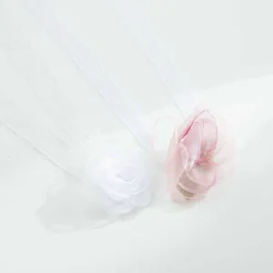 Gedetailleerde close-up van organza lint bloem accessoires in wit en roze, elegante polsband.