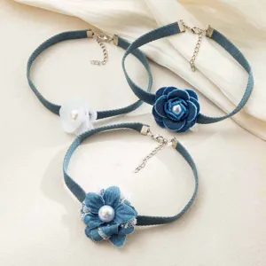 Close-up detail of stylish denim flower choker necklace featuring pearls and metal chains.