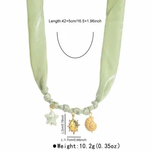 Détail de collier en ruban de tissu vert avec pendentifs étoile, soleil et coquillage en métal.