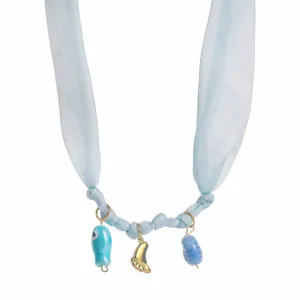 Vue détaillée du collier en ruban de tissu bleu clair avec de charmants pendentifs dorés.