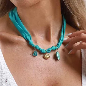 Collier ras de cou en tissu turquoise avec pendentif coquillage pour de jolies vacances d'été.