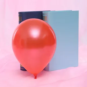 Detailed close-up shot of a vibrant red pearlescent round balloon with decorative books.