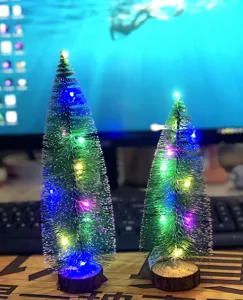 Mini wooden Christmas tree detail showing glowing LED string lights on a rustic desk ornament.
