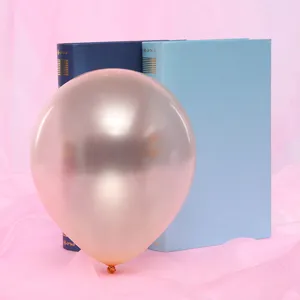 Close-up detail of a metallic rose gold round pearl balloon set against pink fabric and books.