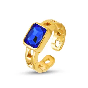 Nahaufnahme eines stilvollen goldenen Titanstahlrings mit strahlend blauem Zirkon in Rechteckform.