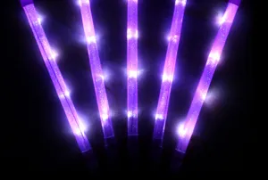 Vista detallada de varitas luminosas LED moradas accesorios de animación para conciertos oscuros.