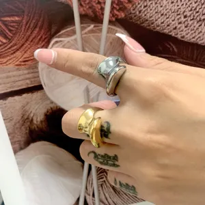 Detailopname van grove geometrische metalen ringen in goud en zilver om de vinger.