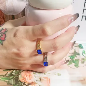 Detailansicht von Titanstahlringen mit rechteckigen blauen Zirkonsteinen und Textur.