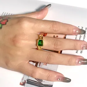 Detailaufnahme eines luxuriösen vergoldeten Titanstahlrings mit grünem rechteckigen Zirkon.