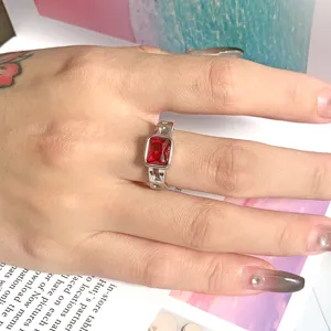 Detailaufnahme eines luxuriösen Titanstahlrings mit rotem Zirkon und strukturierter Band.