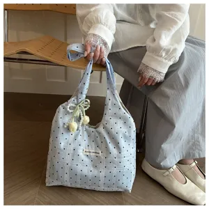 Detail view of a light blue polka dot tote bag with lace overlay and cute tulip charm.