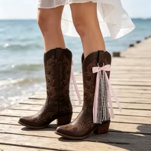 Bottes de cowboy marron avec broderie exquise et nœud papillon rose avec des perles.