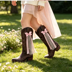 Vue détaillée de bottes western marron avec un nœud rose et de délicats rubans de perles.