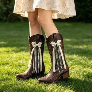 Detailed view of brown western cowboy boots with polka dot bows and pearl lace accessories.