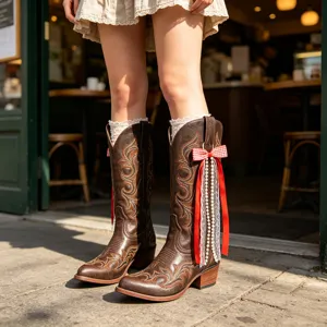 Bottes de cowboy de style occidental avec nœud rouge, ruban de dentelle et pendentif.