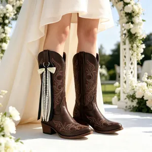 Detailansicht brauner Westernstiefel mit eleganten schwarzweißen Schleifen und Perlenquasten neu.