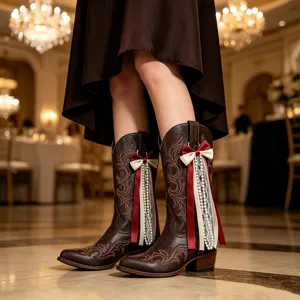Nahaufnahme brauner Western-Stiefel mit filigraner Stickerei, Schleifen und Perlenperlen.