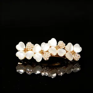 Gold-tone floral hair clip detailed with white cat's eye stone heart petals and pearls.
