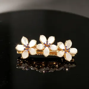 Elegant gold-tone flower hair clip featuring sparkling purple rhinestones for styling.