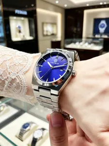 Close-up detail of men's steel strap watch with striking blue dial and elegant bracelet design.