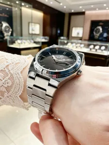 Detailed wrist view of a stylish men's stainless steel watch featuring a dark dial and luminous hands.