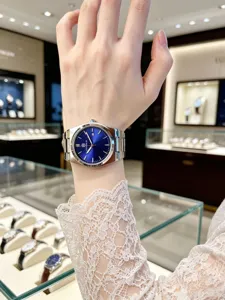 Wrist close-up of men stainless steel watch with blue sunburst dial and calendar window.