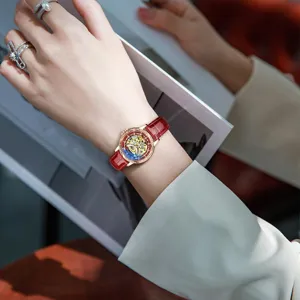 Elegante Damenmechanikuhr mit Skelettzifferblatt, rotem Lederarmband und Diamantlünette.
