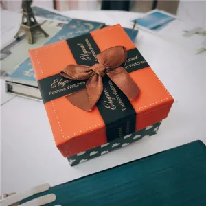 Oranje geschenkdoos detail, vierkante horlogeverpakking met bruine strik en hartjespatroon.