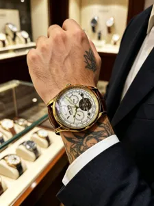 Detailed wrist view of men's automatic mechanical watch with gold case and leather strap.