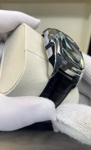 Close-up detail of luxury tonneau quartz watch with polished metal case and black leather strap.