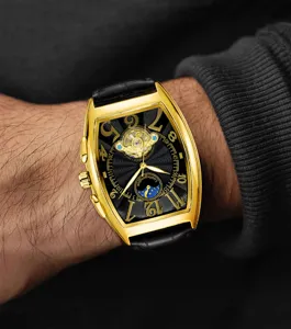 Detailed shot of gold tonneau mechanical watch with skeleton dial and moon phase on wrist.
