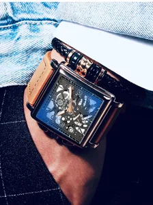 Close up detail of mens square dial quartz watch with brown leather strap and black bracelet.