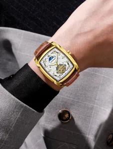Closeup of men's tonneau mechanical watch with hollow dial and brown leather strap.