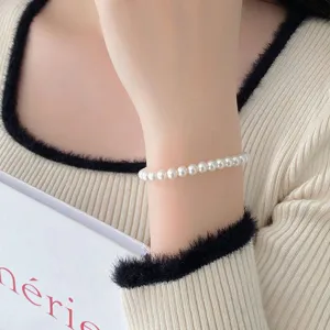 Élégant bracelet de perles blanches au poignet, design minimaliste chic pour le quotidien.