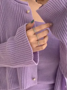 Nahaufnahme von funkelnden stapelbaren Silberringen am Finger mit Strickoberteil.
