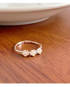 Gros plan détaillé de la jolie bague en argent S925 avec trois fleurs de perles délicates.