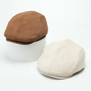 Close-up detail view of stylish suede flat caps in brown and beige, featuring clean stitching.