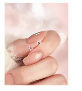 Nahaufnahme der zarten Silberstern-Ohrringe mit funkelnden rosa Zirkonia-Steinen.