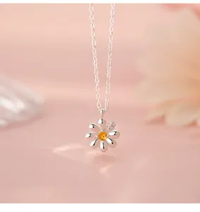 Detail shot of a dainty silver daisy pendant necklace with a yellow stone center.