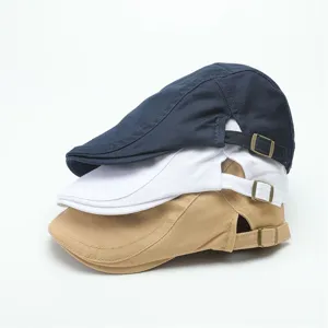 Gedetailleerd overzicht van gestapelde vintage petten in marine, wit en kaki met metalen gespen.
