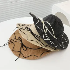 Detailansicht von drei gestapelten Strohhüten in Schwarz, Beige und Braun mit Perlen.