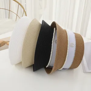 Detail view of stylish woven bucket hats with pearl chains and metal M logo in multiple colors