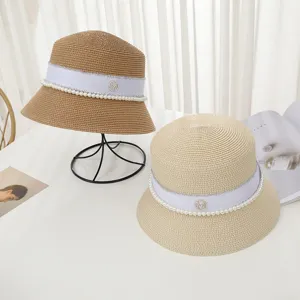 Detailed view of summer straw bucket hats with pearl and rhinestone M logo decoration.