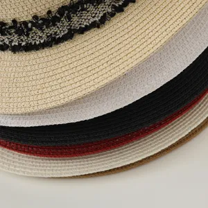 Gros plan détaillé de chapeaux de paille pour femmes empilés en plusieurs couleurs avec dentelle.