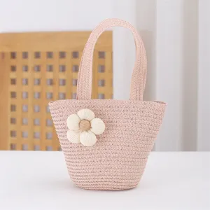 Charming pink straw woven handbag detail featuring a cute fabric flower for beach vacation.
