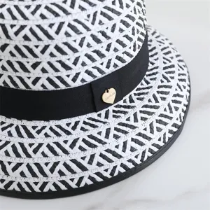 Vue de détail rapprochée du chapeau de paille tissé noir et blanc avec un ruban.