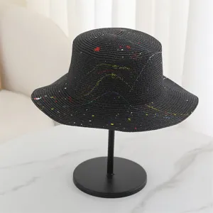Close-up detail view of a black straw hat featuring colorful paint splatter graffiti design.