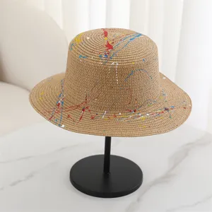Detail view of the summer flat top straw hat featuring creative colorful paint splash design.